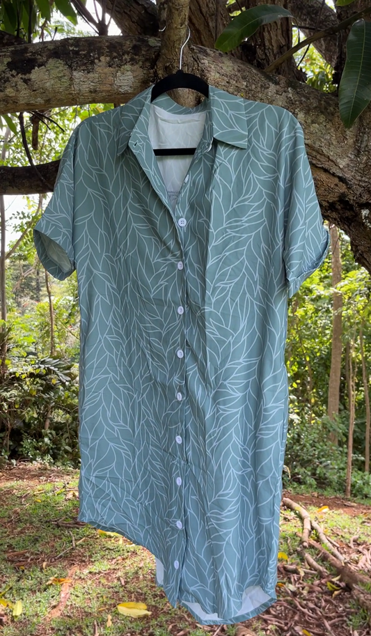 green patterned womens aloha shirt dress hanging on a tree branch with a natural background